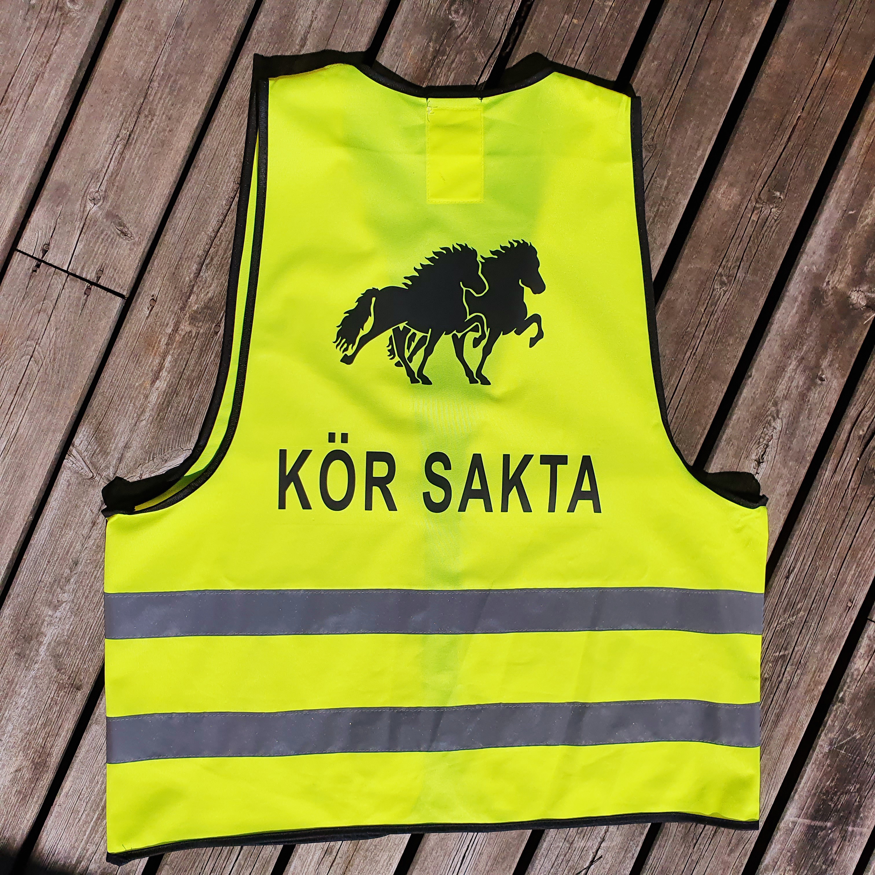 Reflexväst  gul med 2 reflexband runt västen .Tryck i svart med motiv 2 islandshästar och text KÖR SAKTA