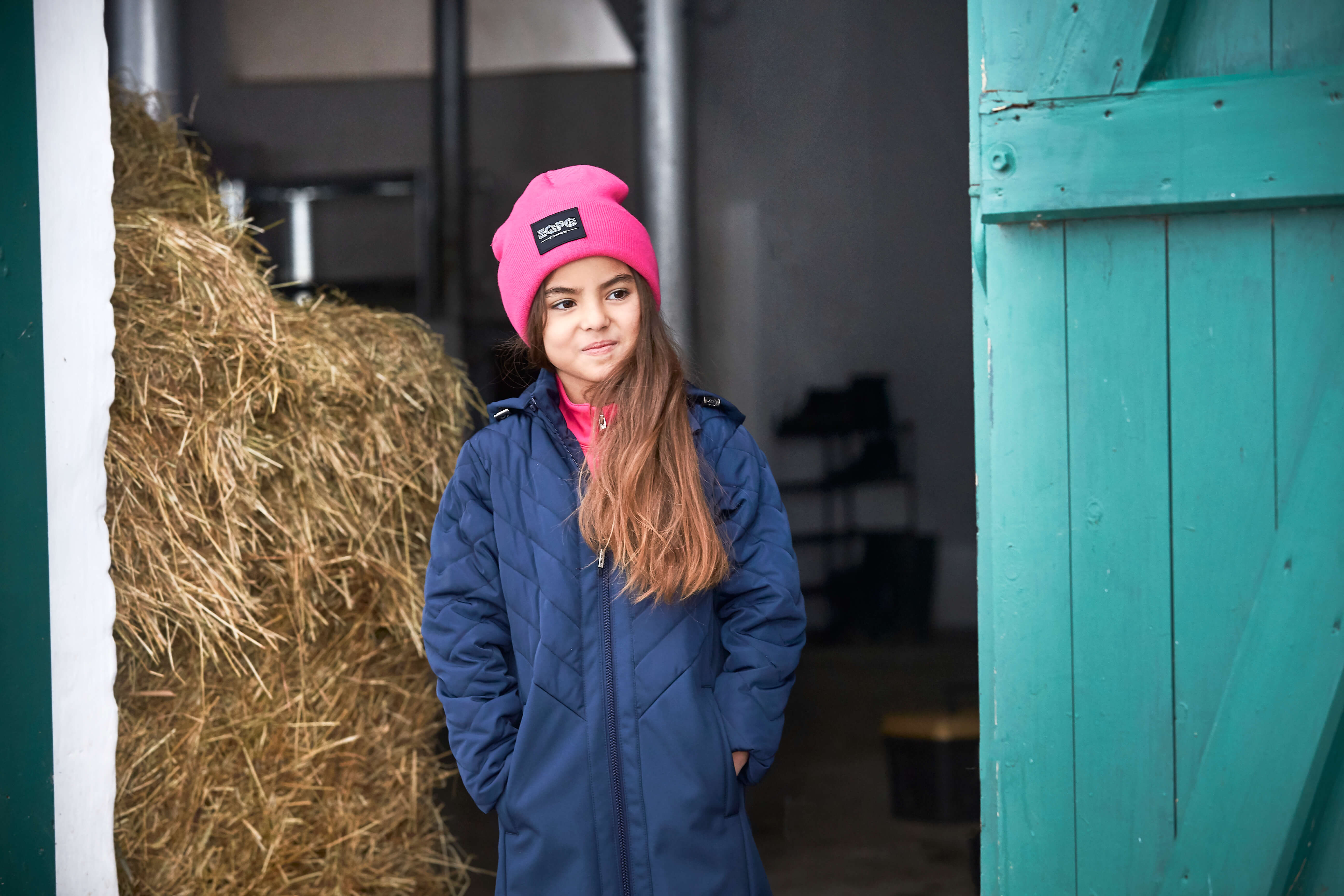 Flicka med vinterjacka i stallet