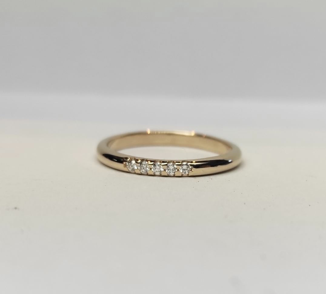 Ring Fina i 18K guld med briljantslipade diamanter liggande mot underlag