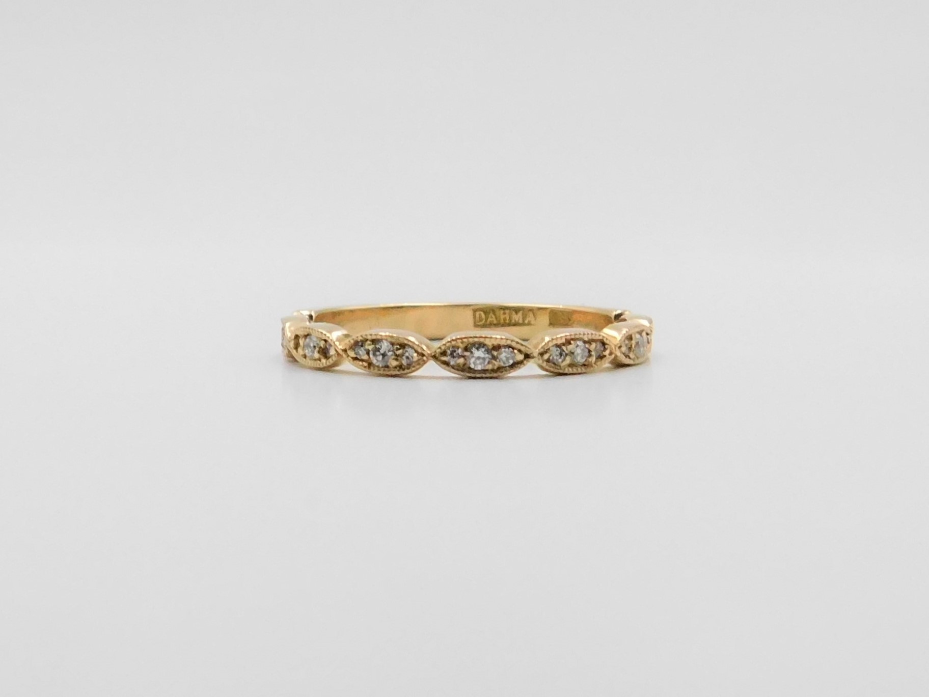 Ring Stina i 18K guld med vågformad profil och briljantslipade diamanter, liggande mot underlag