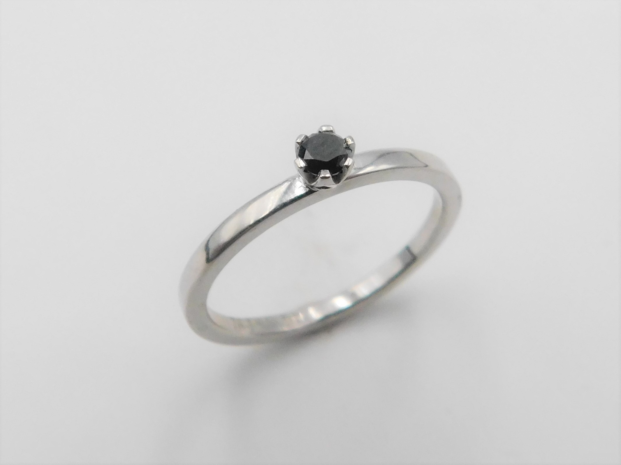 Ring Elly i vitguld med svart diamant stående mot ljust underlag