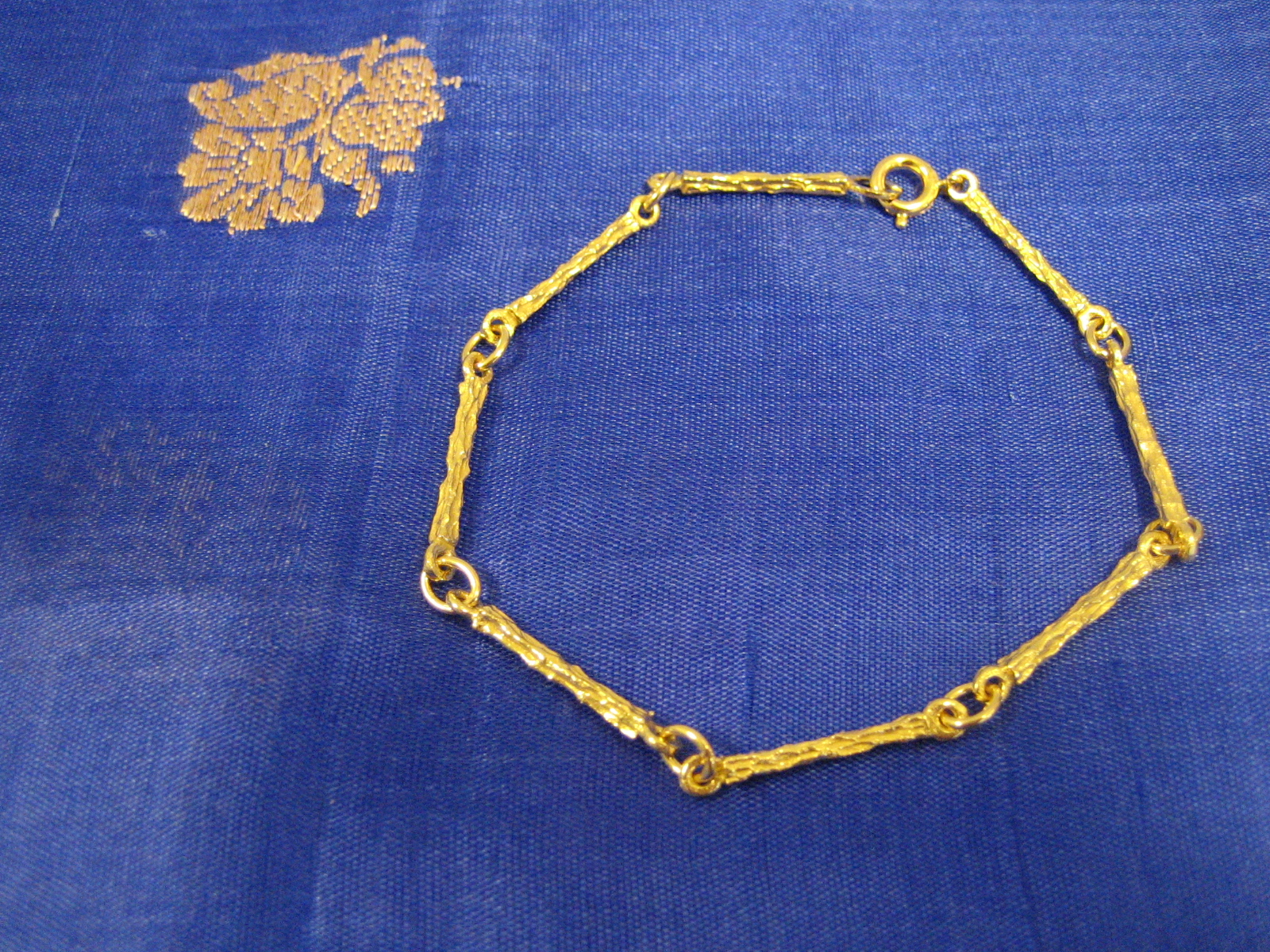 Armband i 18 karat guld.Stavar med rågulds yta.