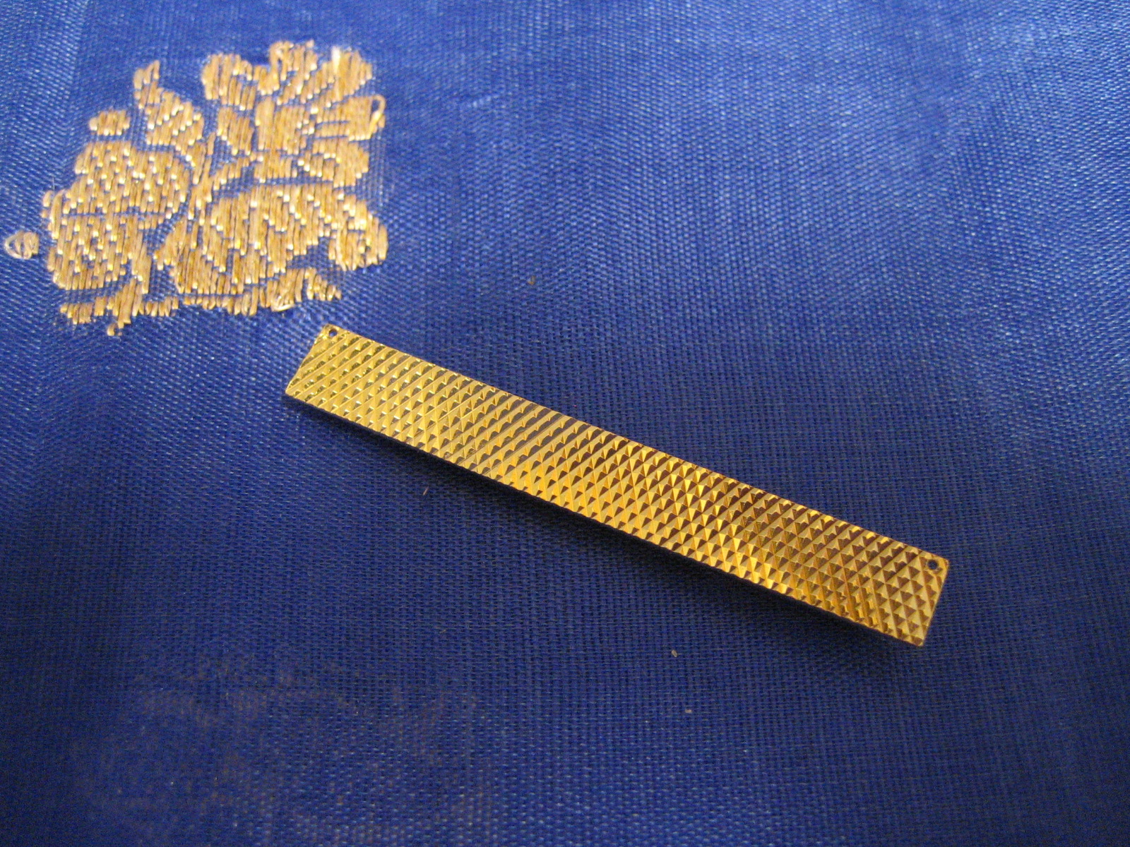 Slipshållare i 18 karat guld med slipat rutmönster.