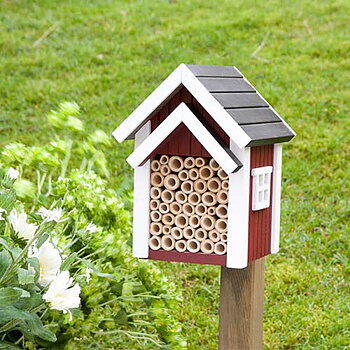 Biholk Röd, holk för bin i trä i naturmiljö med blommor