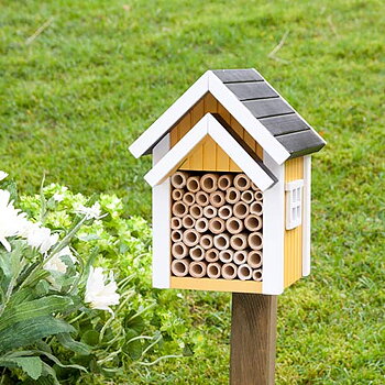 Biholk Gul, holk för solitärbin i trä målad med miljövänlig färg i naturmiljö med gräs och blommor