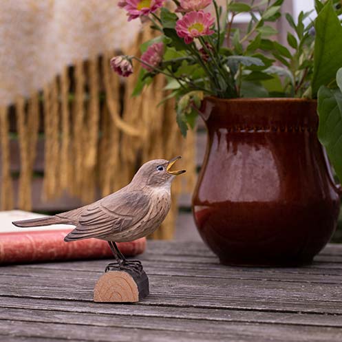 DecoBird Thrush Nightingale, hand carved wooden bird painted with environmentally friendly colours, outdoors on a table