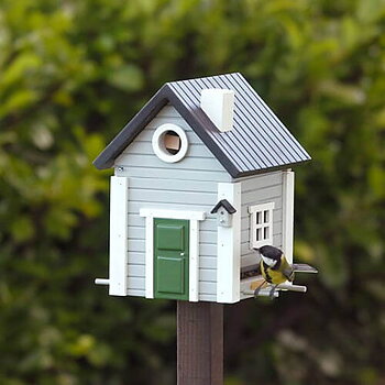 Multiholk Grått Hus, fågelmatare i trä målad med miljövänlig färg, i naturmiljö med en fågel på