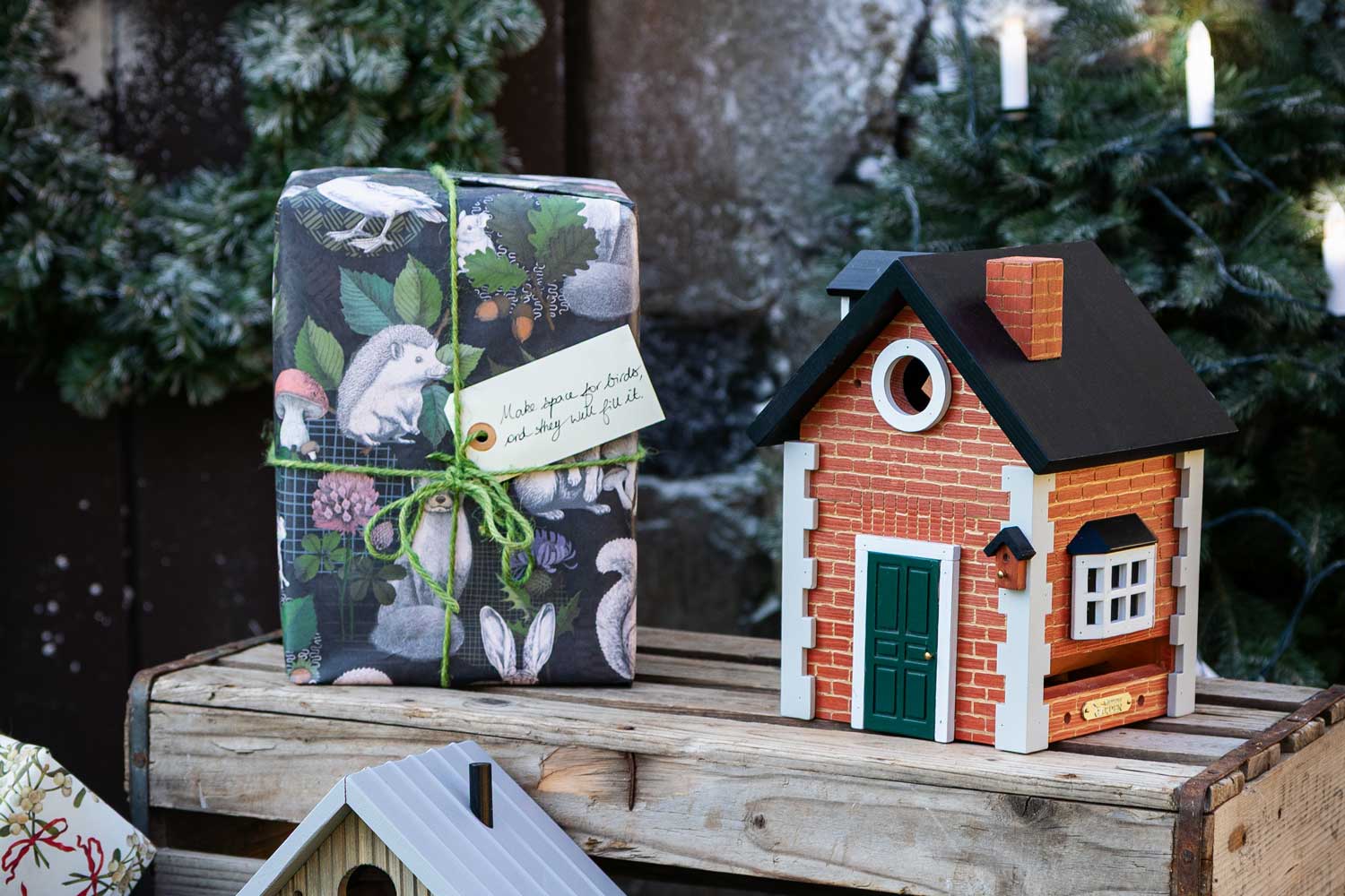 Wildlife Garden Multiholk Brick Cottage beside a wrapped Christmas gift in a winter setting