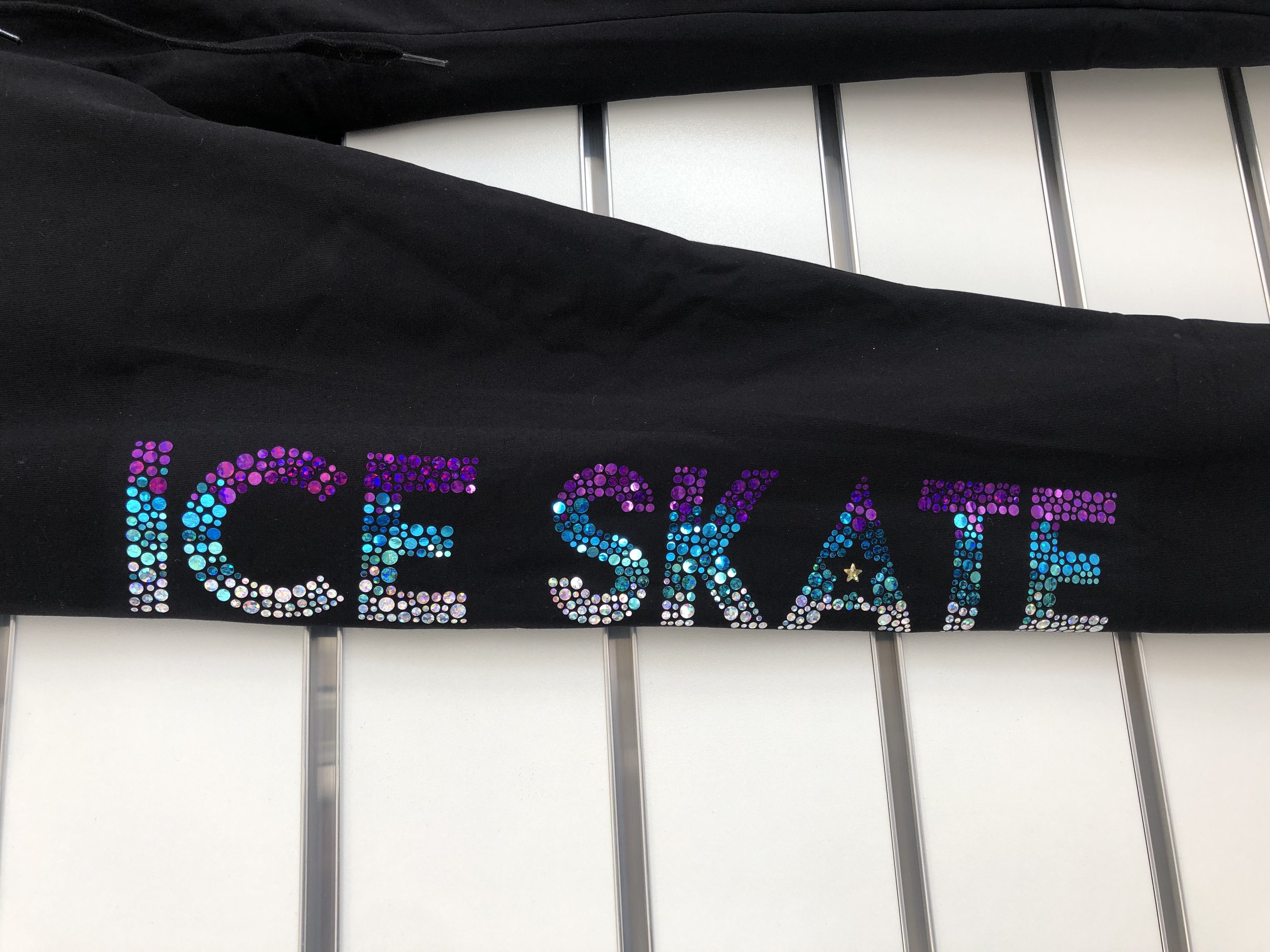 Texten ICE SKATE i glittriga hologrampaljetter