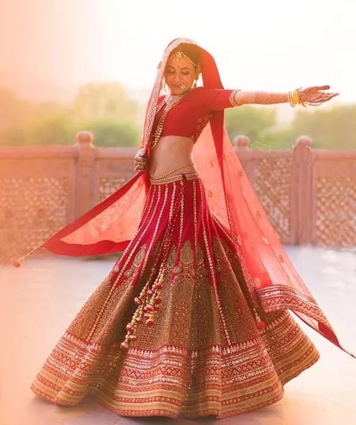 Indisk kvinna iklädd en röd lehenga och dupatta