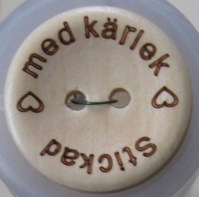 Dekorativ knapp i trä med text. - 2
