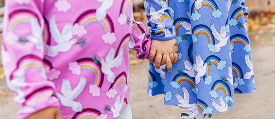 Farbenfrohe Kinderkleidung mit Friedenstauben und Regenbögen