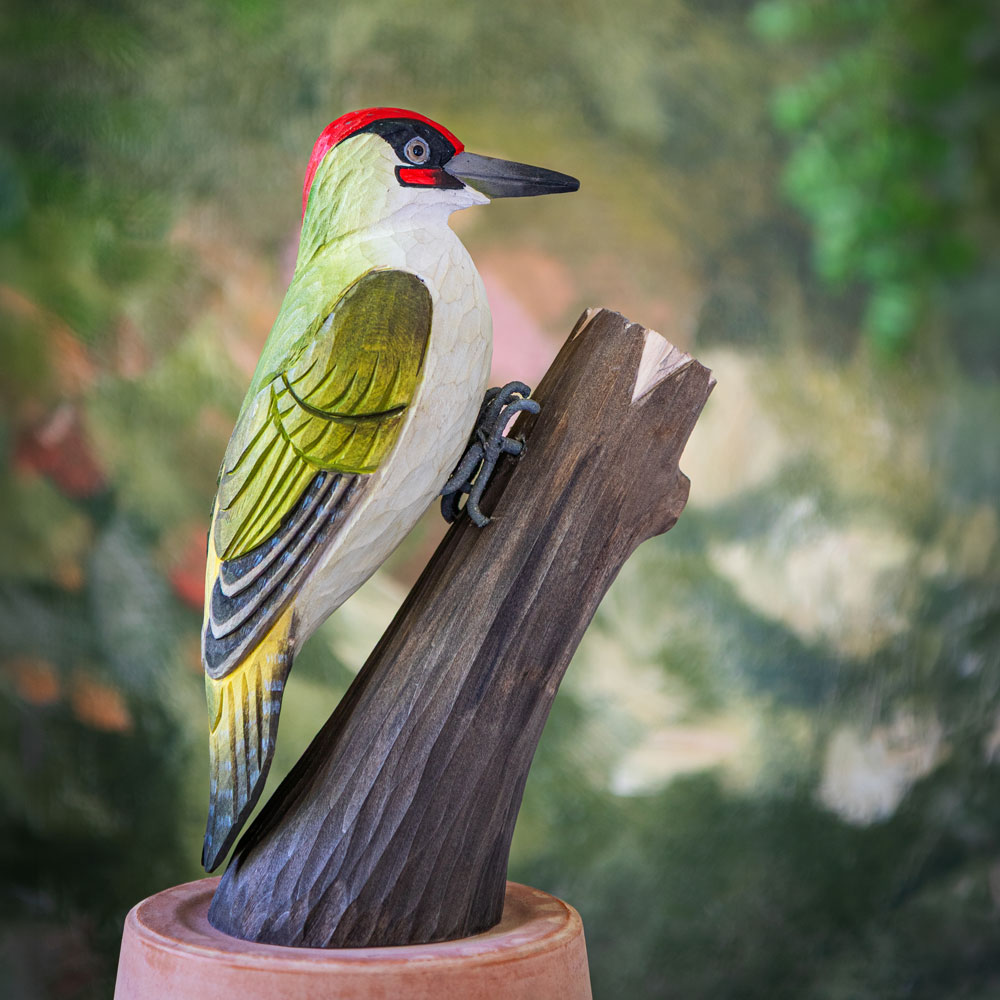 DecoBird Green Woodpecker placed on a terracotta pot in front of a painted green background.