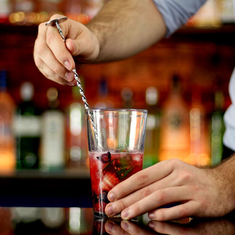 Blandar ingredienser till drink med barsked från cocktailset
