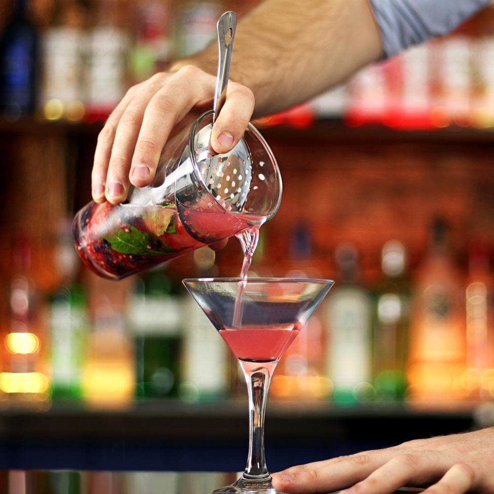Häller upp cocktail med julep strainer