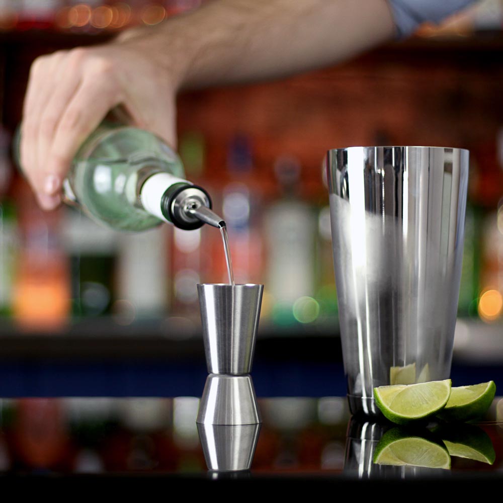 Mäter ingredienser till drink med jigger barmått från cocktailset deluxe