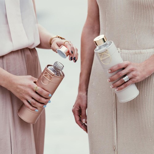 Kahdella ihmisellä on kädessään lasivesipulloja beige-kansilla