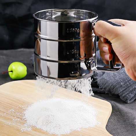 Käsin käyttämällä ruostumattomasta teräksestä valmistettua jauhoseulaa