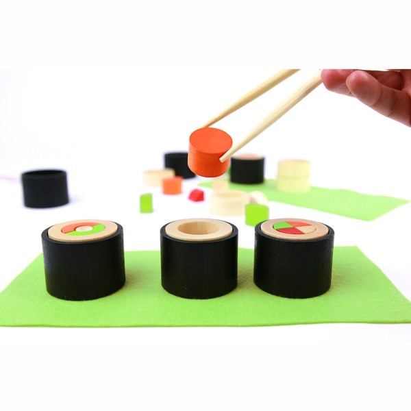 Hånd med spisepinde leger med træstykker af sushi