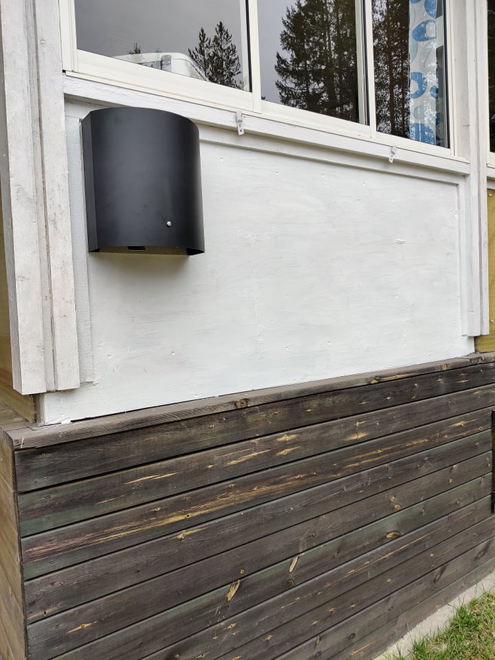 Skorstensfri pelletskamin Lilla Frö, vit med grå front. Pelletskamin utan skorsten. Bilden visar draget mot en vit vägg. Inglasad altan.