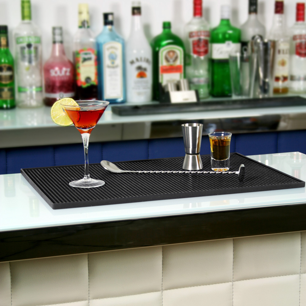 Stor barmatta i gummi på en bardisk med blandad cocktail och drinkredskap