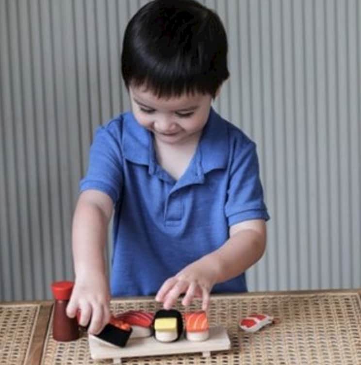 Barn som leker med leksaksmat sushi av trä