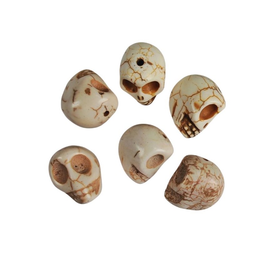Beige dödskallepärlor i pressad howlit, cirka 17×18 mm med hål på 1,5 mm, visade i närbild mot vit bakgrund.