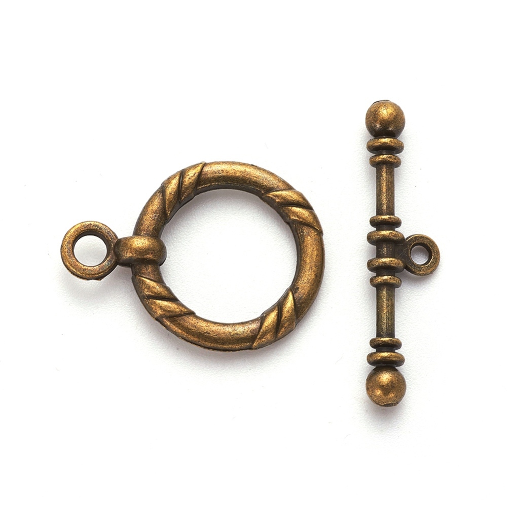 Stort stavlås i bronsfärg, ring och stav med vriden dekor, ring ca 21 mm och stav ca 34 mm, visat i närbild.