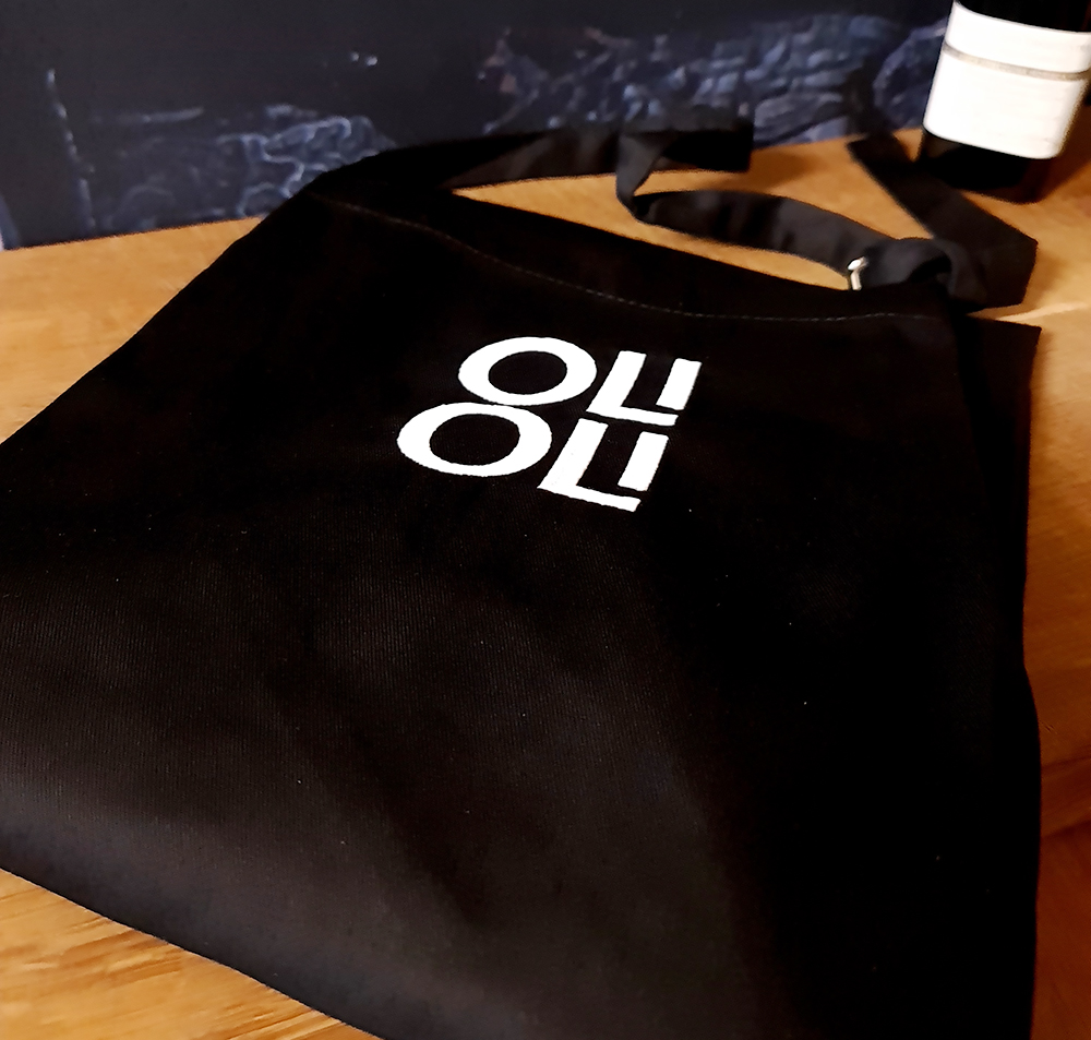 Svart tygförkläde med OLIOLI i vit brodyr på bröstet