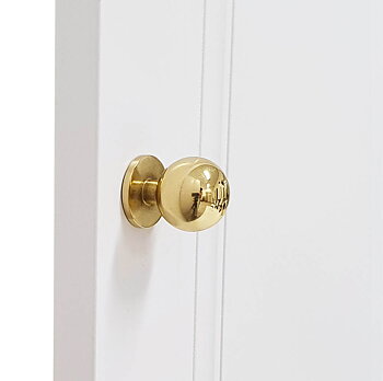 Garderobsknopp C18 är en rund, blank och guldfärgad knopp i mässing som sitter på en platta