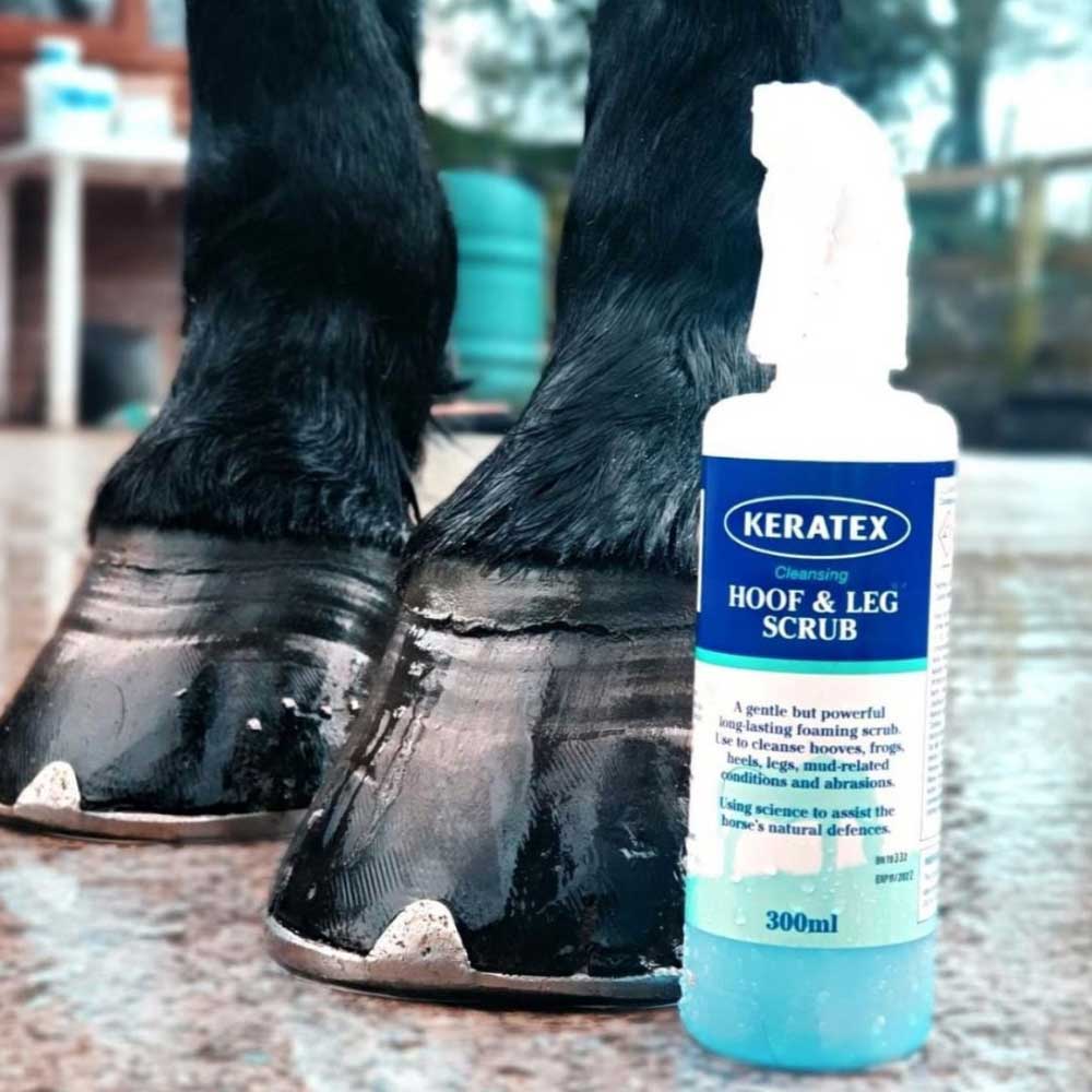 Keratex Hoof & Leg Scrub 300 ml flaska bredvid hästhovar i ett stall.