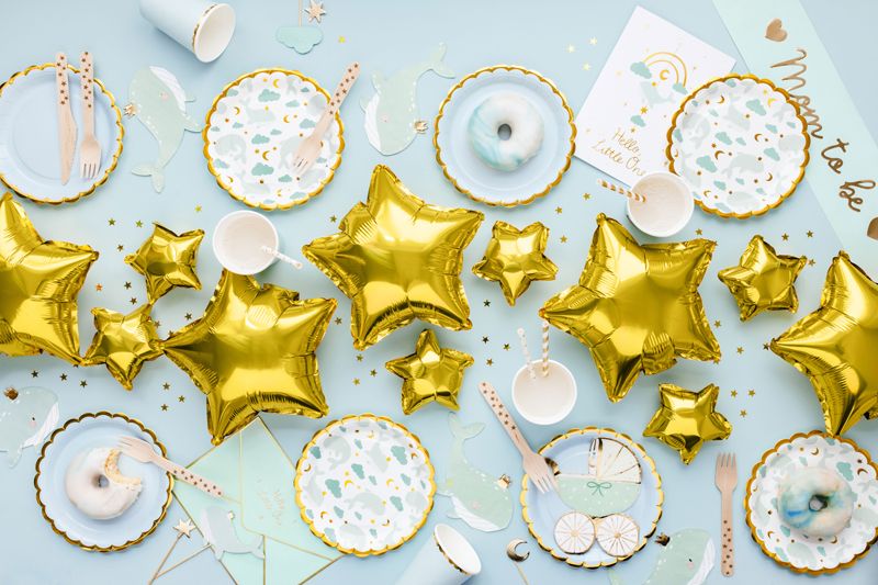 Ljusblå babyshowerdukning med guldfärgade stjärnballonger och Mom To Be-dekoration.