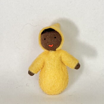 Mörk baby med mörkt hår och gul pyjamas - en liten handgjord dekorationsfigur av ull 