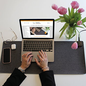 Brett uppvärmt skrivbordsunderlägg med mörkgrå textilyta på en arbetsplats