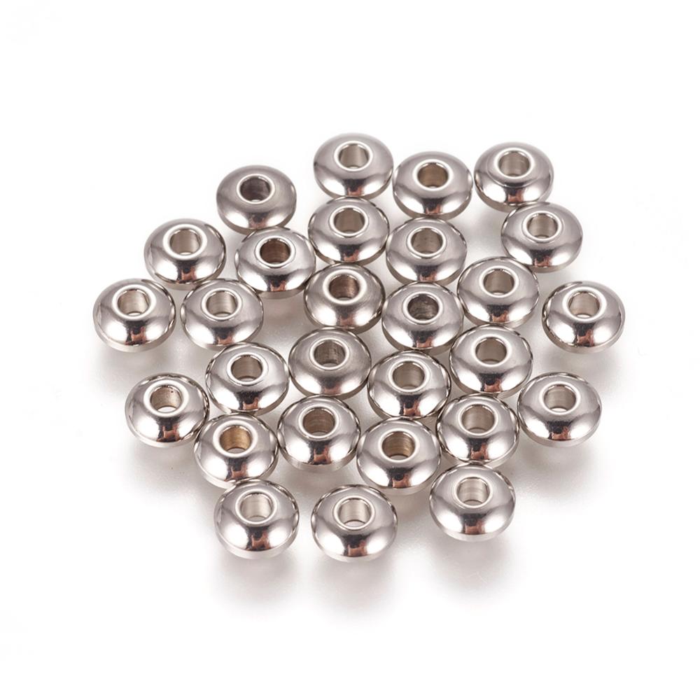 Små runda metallrondeller i rostfritt stål, 6 × 3 mm, med hål på ca 2 mm, 20 stycken pärlor samlade på vit bakgrund.
