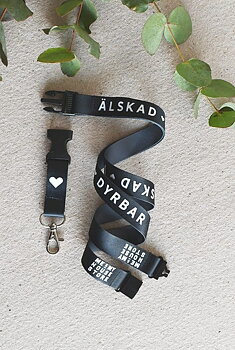 NYCKELBAND I SVART: ÄLSKAD, VÄRDEFULL, DYRBAR. OCH ALLMÄNT BRA!  