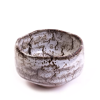 En beige och handgjord matchabowl som har bruna vackra ådringar i ytan.