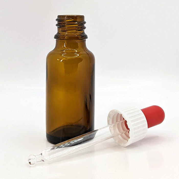 en tom mörk glasflaska där pipetten ligger bredvid