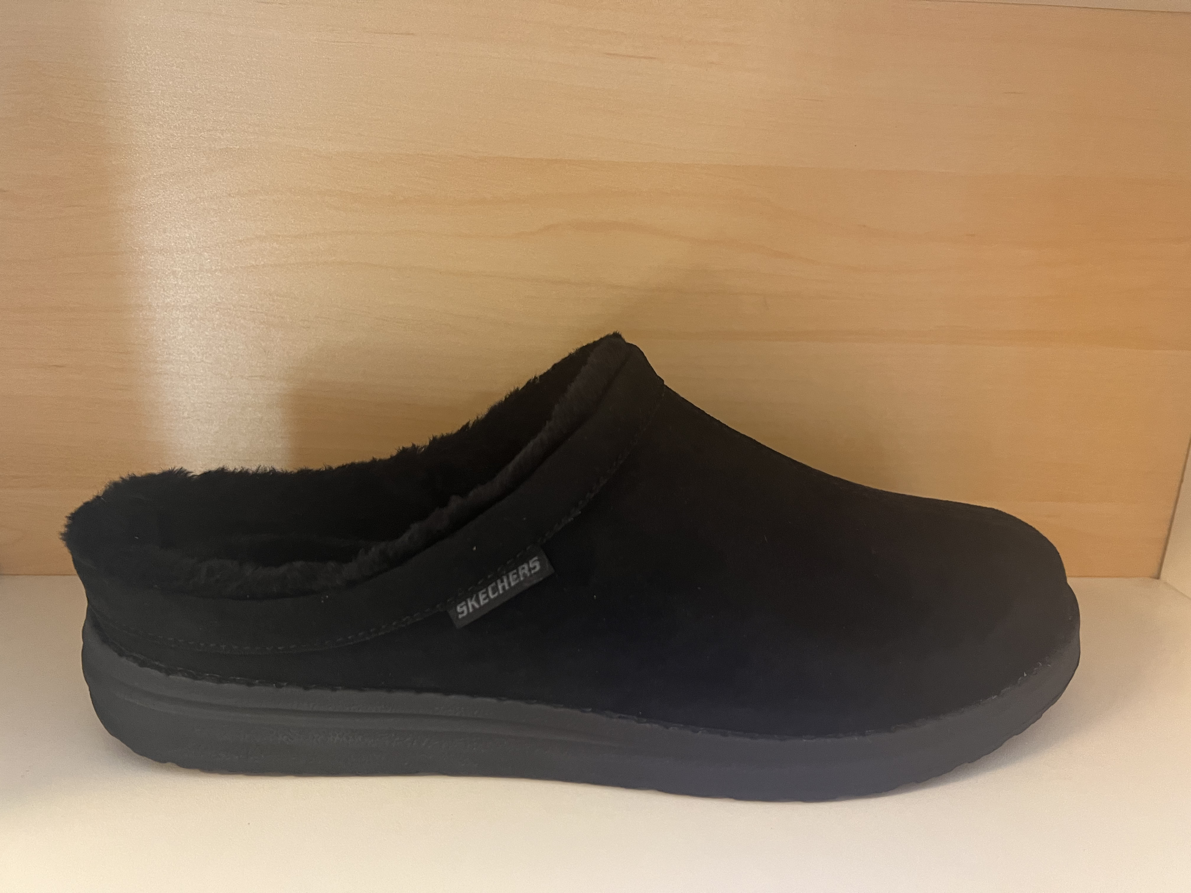 Skechers Herrtoffel. Relaxed Fit=bred framfot.  Slitstark yttersula och med Luxe Foam i innersulan.  Klädd med pälsimitation.