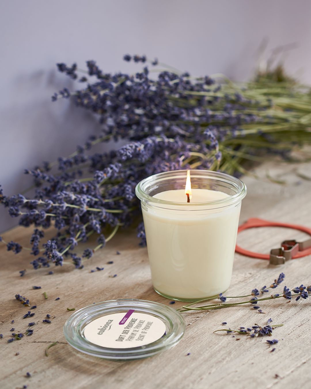 Ett tänt eubiona doftljus scent of provence på bord med torkad lavendel