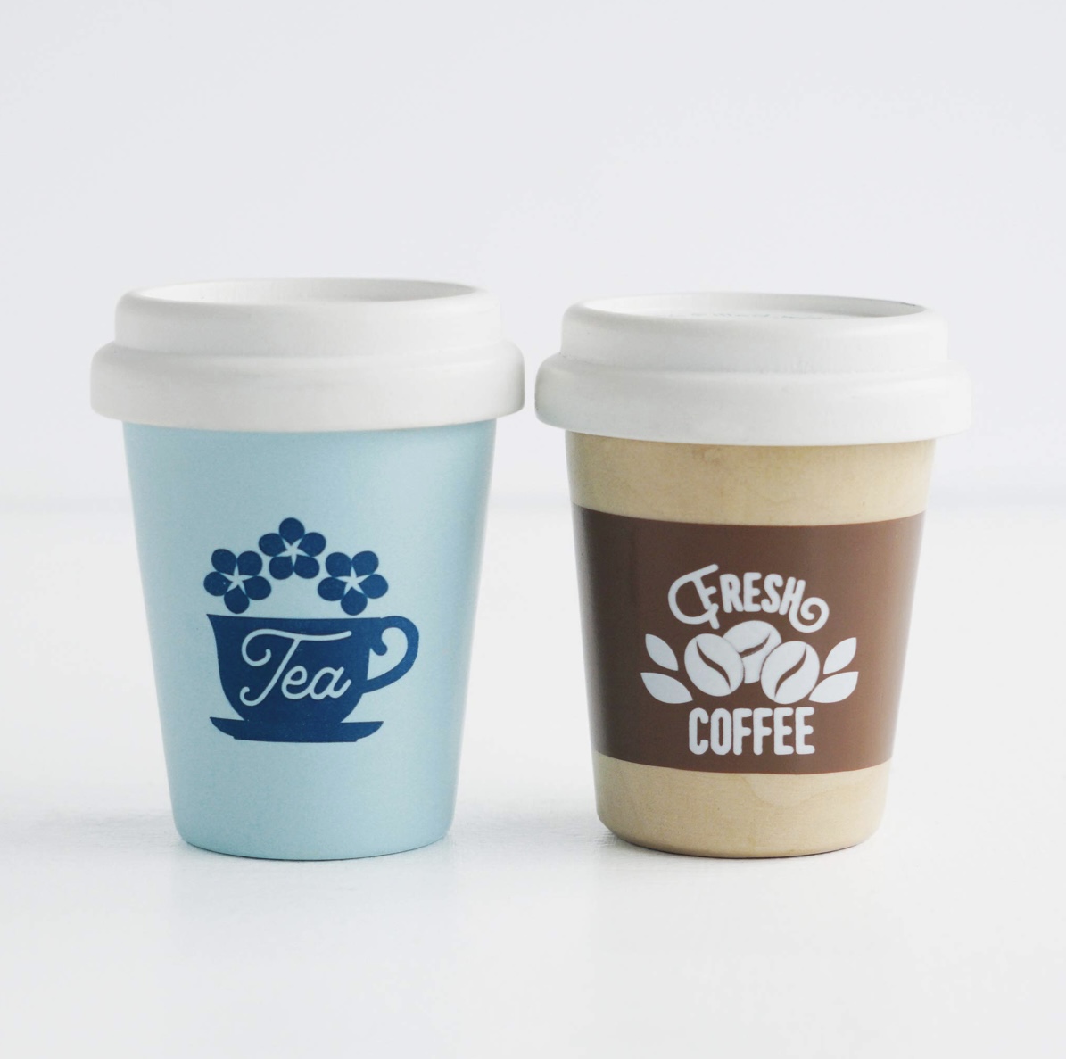 Take away-muggar i massivt trä, en te mugg i blå toner och en kaffemugg i bruna toner.
