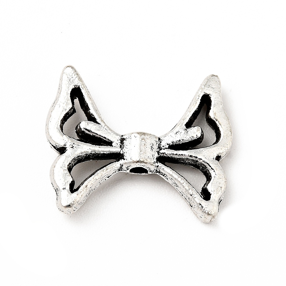 Tio små antiksilverfärgade vingeberlocker med rosettformade vingar, cirka 12,5×15 mm, visade mot ljus bakgrund.