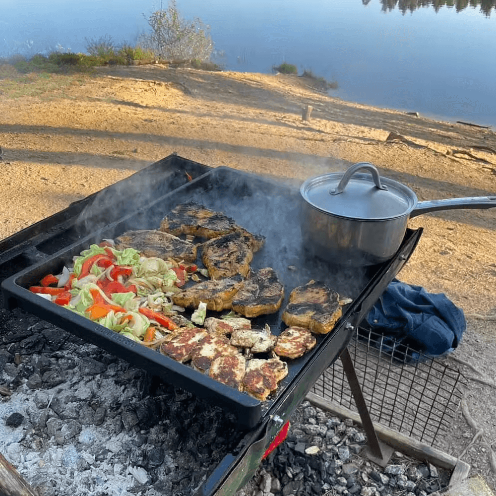 Udendørs madlavning på et stegebord i støbejern placeret over et åbent bål