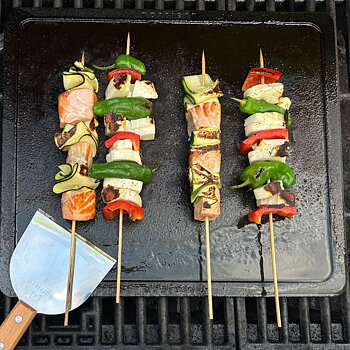 Fire grillspyd med grøntsager, der grilles på et stegebord Gourmet i støbejern.