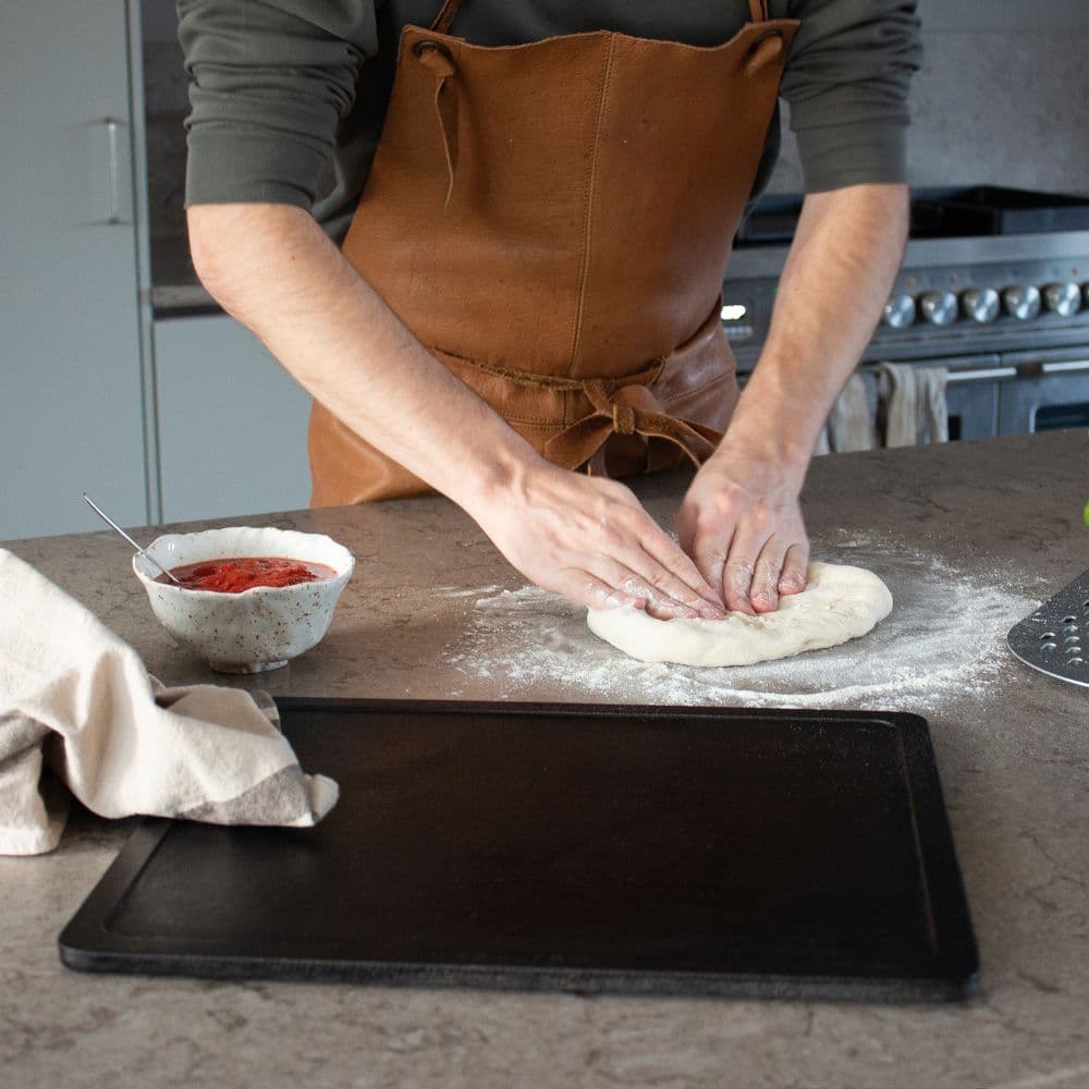 Pizzabage på melet bord ved siden af et stegebord Gourmet i støbejern