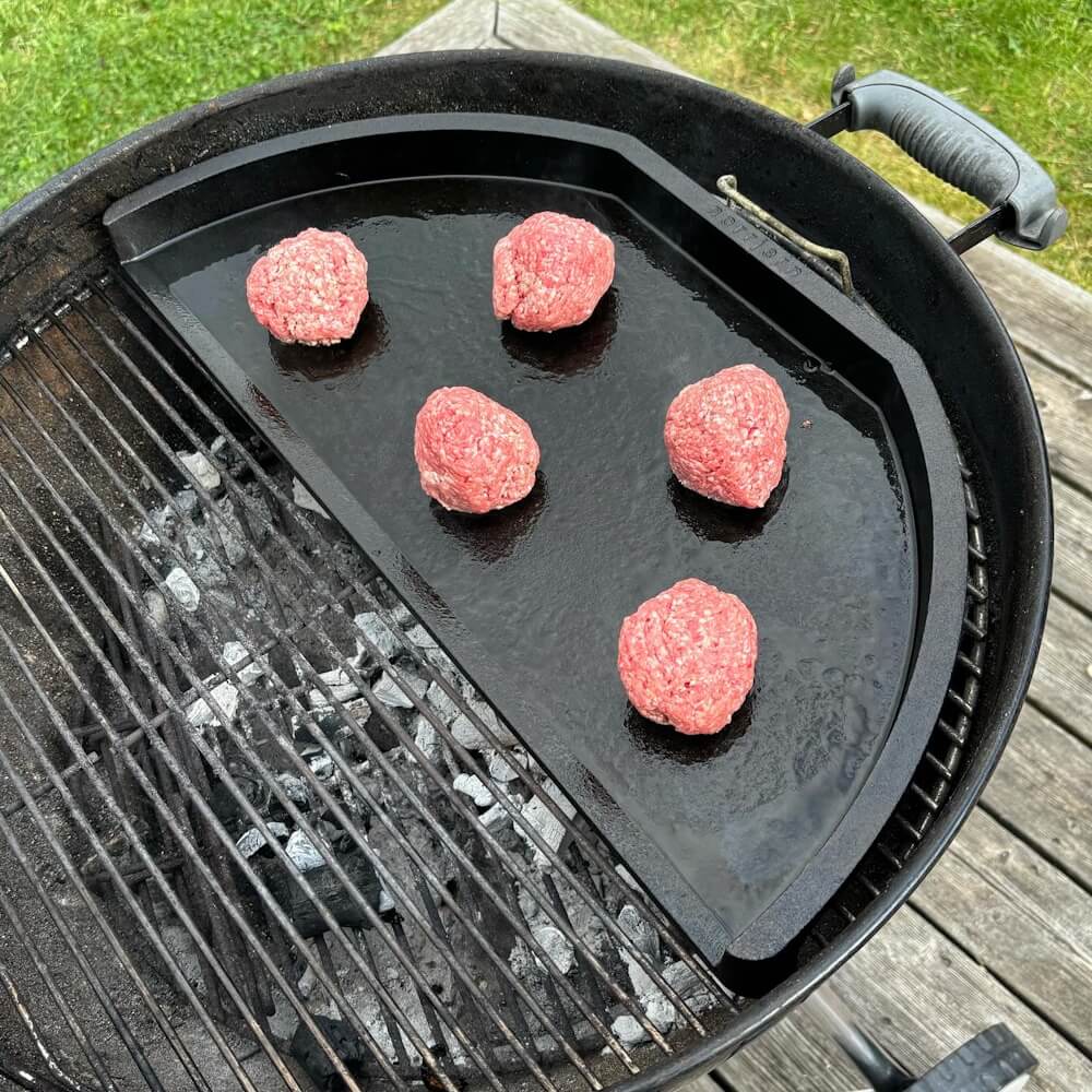  Boller af oksekød ligger klar på et varmt stegebord for at blive presset til burgere.