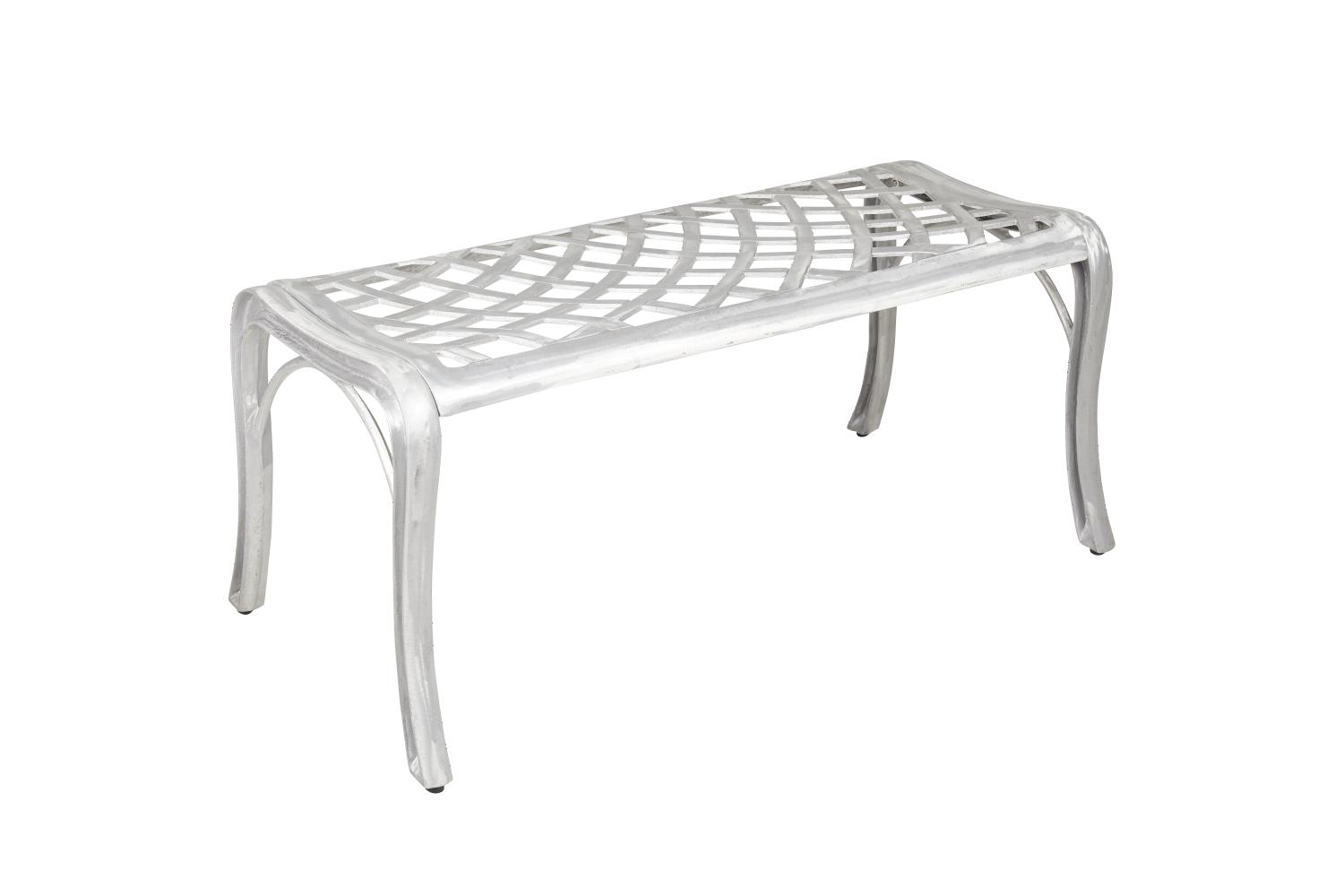 En bänk i ofärgad aluminium. Sitsen har ett snirkligt mönster med något svängda ben.