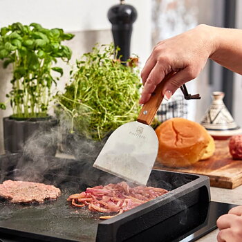 Stegeskraberen er det optimale redskab til at skrabe op og vende smashed burgers på vores stegebord af støbejern.