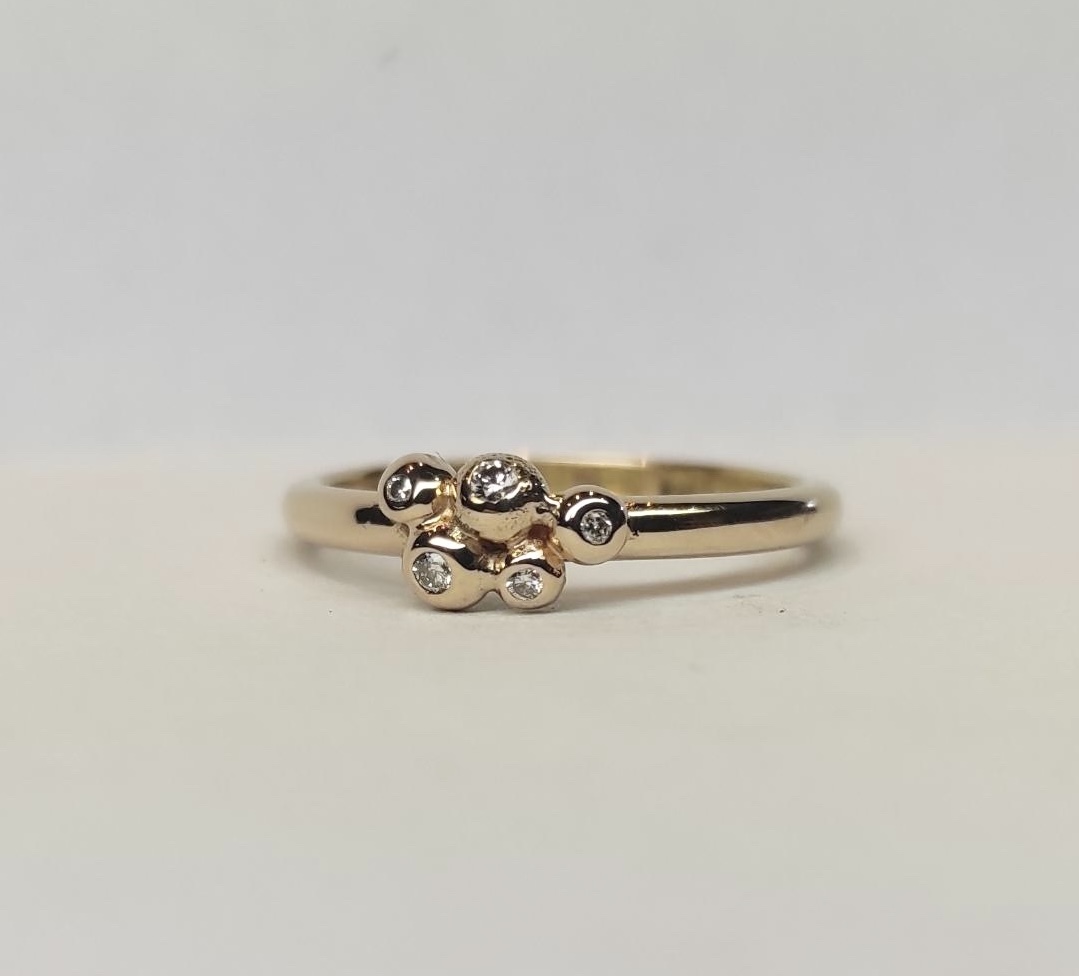 Ring Filippa i 18K guld med briljantslipade diamanter liggande mot underlag