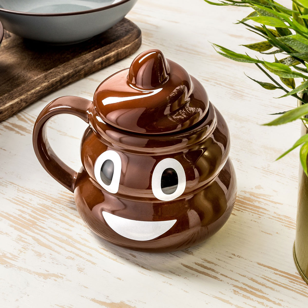 Poop-Emoji-Mugg med locket på ståendes på ett bord